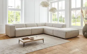 Kleines Kind pielt mit Plüschtier. Großes Ecksofa im hellen natur durchleuchteten Raum mit kleinem Couchtisch.